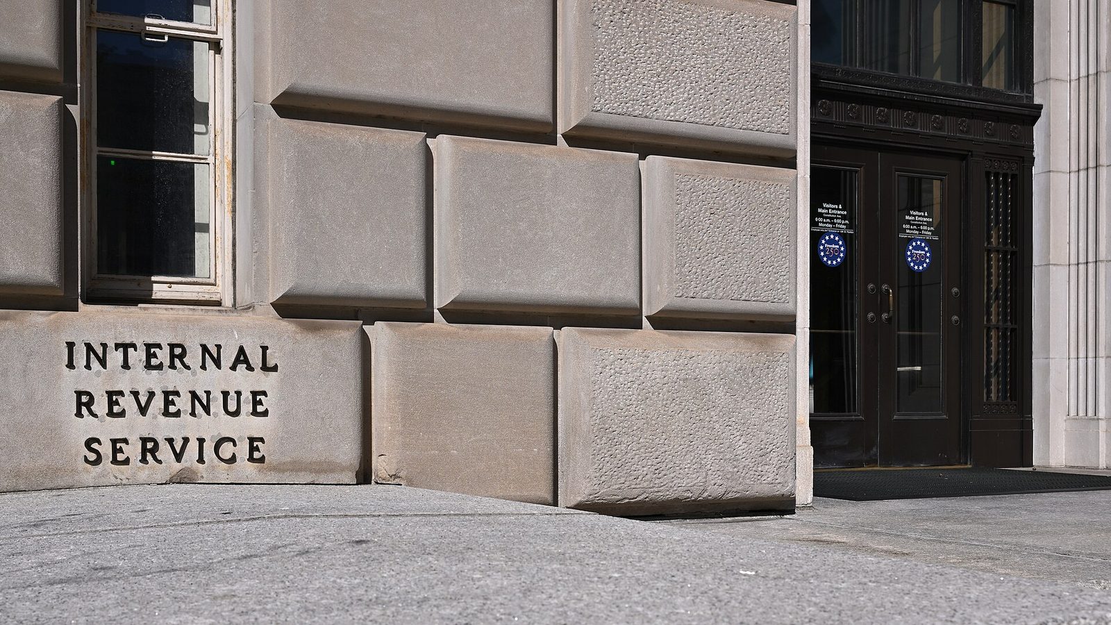 The words Internal Revenue Service carved into the stone base of the IRS building beside its dark double entrance doors on Constitution Avenue in Washington, D.C.